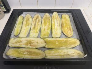 פרוסות חציל מוברשות בשמן זית בתבנית עם נייר אפייה